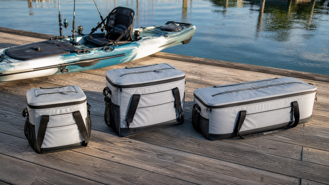Three kayak fish cooler bag sizes arranged beside a fishing kayak